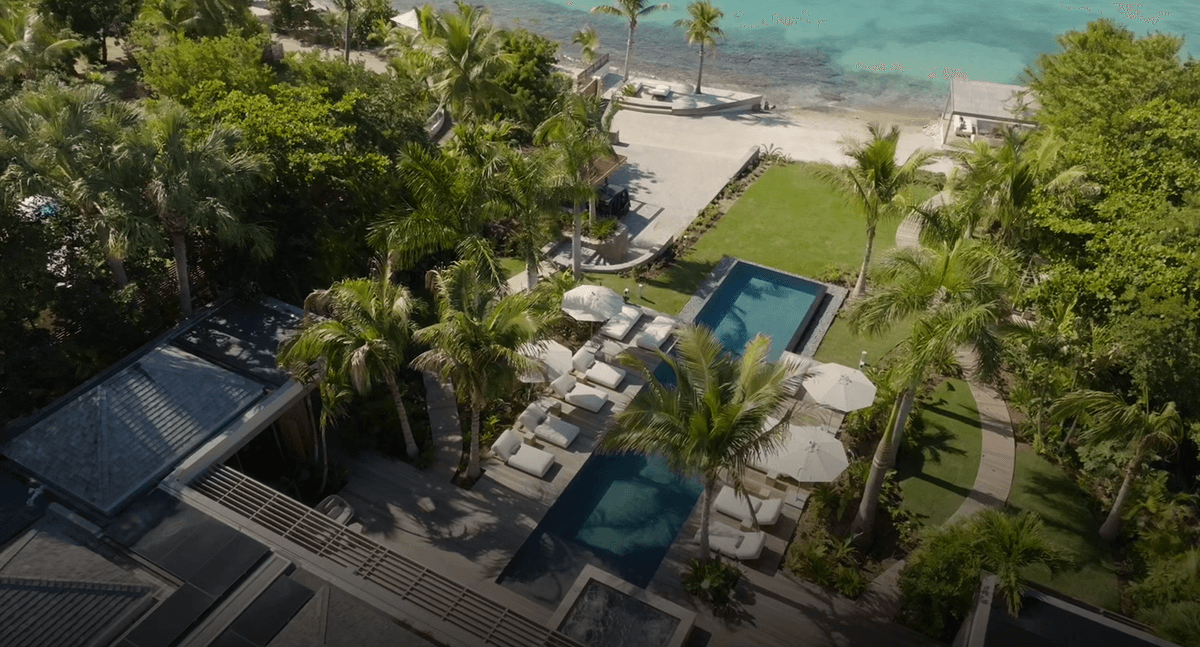 Luxury beachfront villa with pool, lush tropical gardens, and direct access to a sandy beach.
