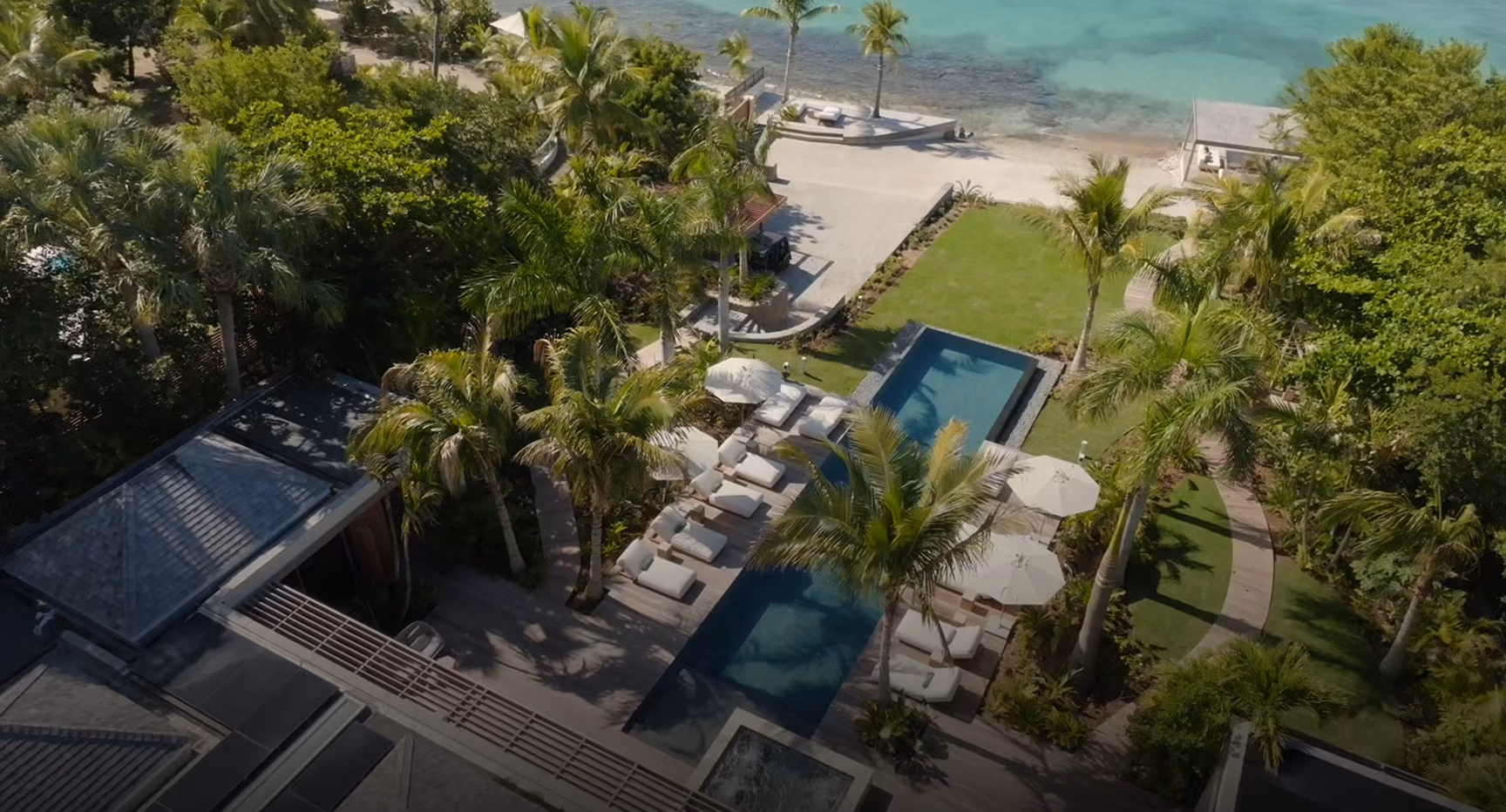 Luxury beachfront villa with pool, lush tropical gardens, and direct access to a sandy beach.